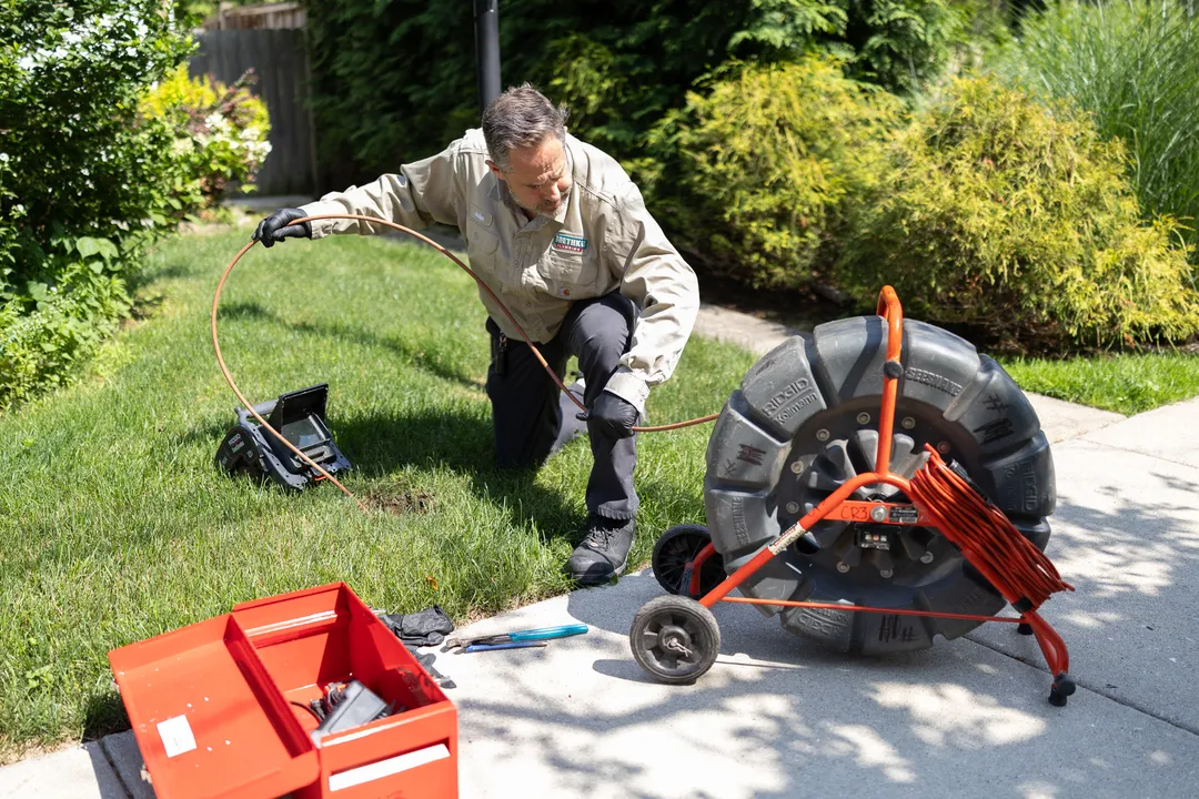 Baethke Plumbing technician running a drain camera on a front walkway