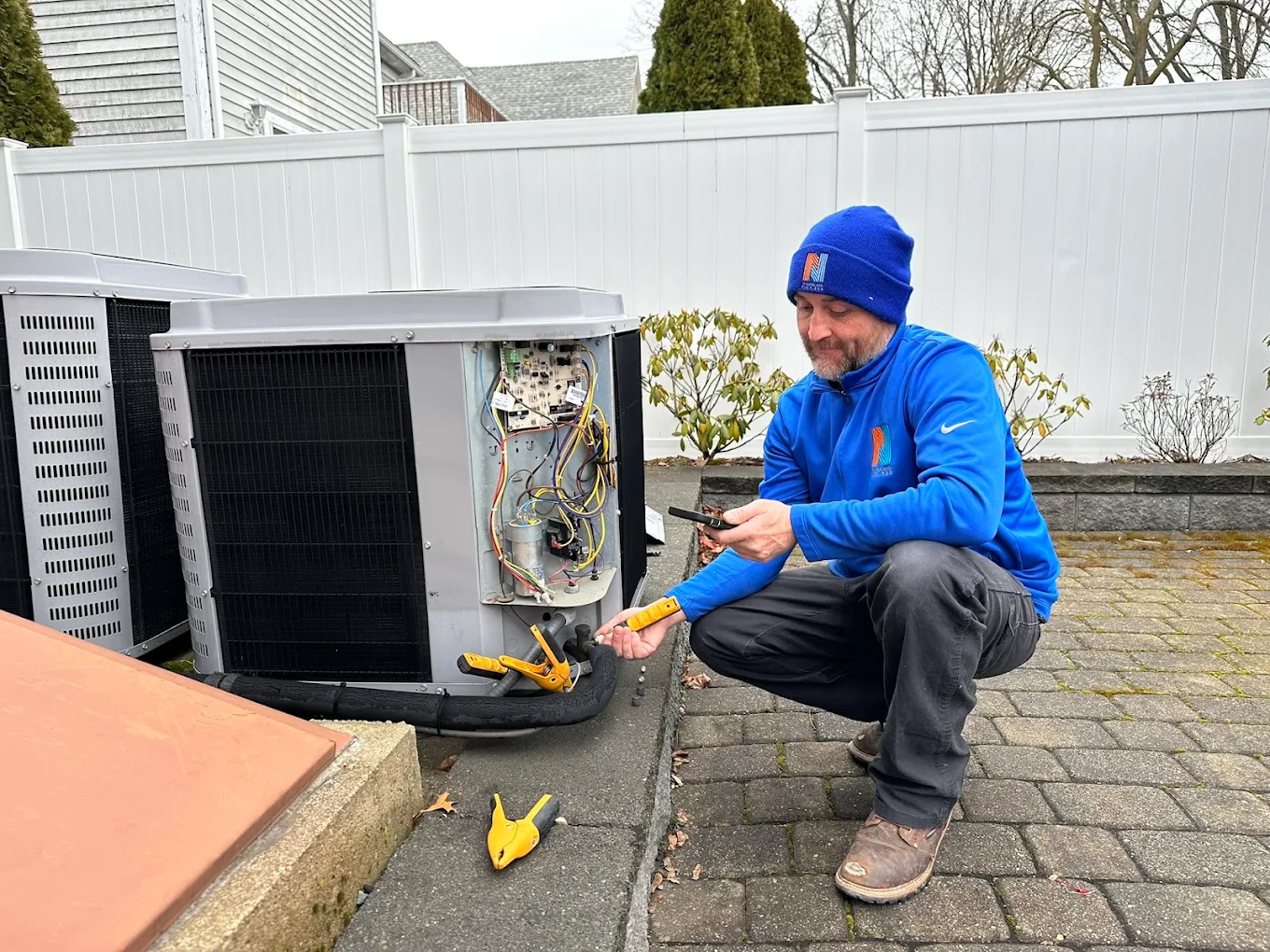 New England Ductless technician servicing an outdoor heat pump unit